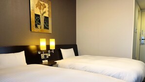 Ein Hotelzimmer mit zwei Betten, einem Nachttisch mit Lampe und einem an der Wand hängenden Kunstwerk.