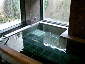 A glass-bottomed hot tub with a view of greenery outside. - Hotel Route Inn Aizuwakamatsu (Aizuwakamatsu)