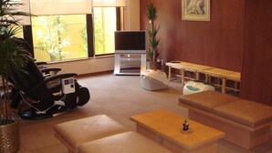 A living room with a sofa, a massage chair, a TV, and a small table with a plant. - Hotel Route Inn Aizuwakamatsu (Aizuwakamatsu)