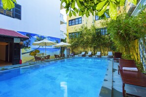 Una piscina al aire libre, sombrillas, sillones reclinables de piscina