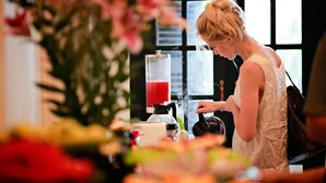 Una persona en una estación de barista con una máquina de café y un recipiente rojo para bebidas.