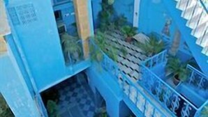 A blue building with a staircase and a balcony.