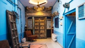 A narrow hallway with a blue door, a ceiling fan, and a chair.