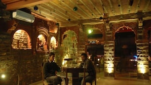 A room with stone walls, a round table, and two chairs.