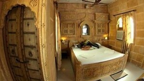 A traditional room with a large bed, a wooden wardrobe, and a ceiling fan.