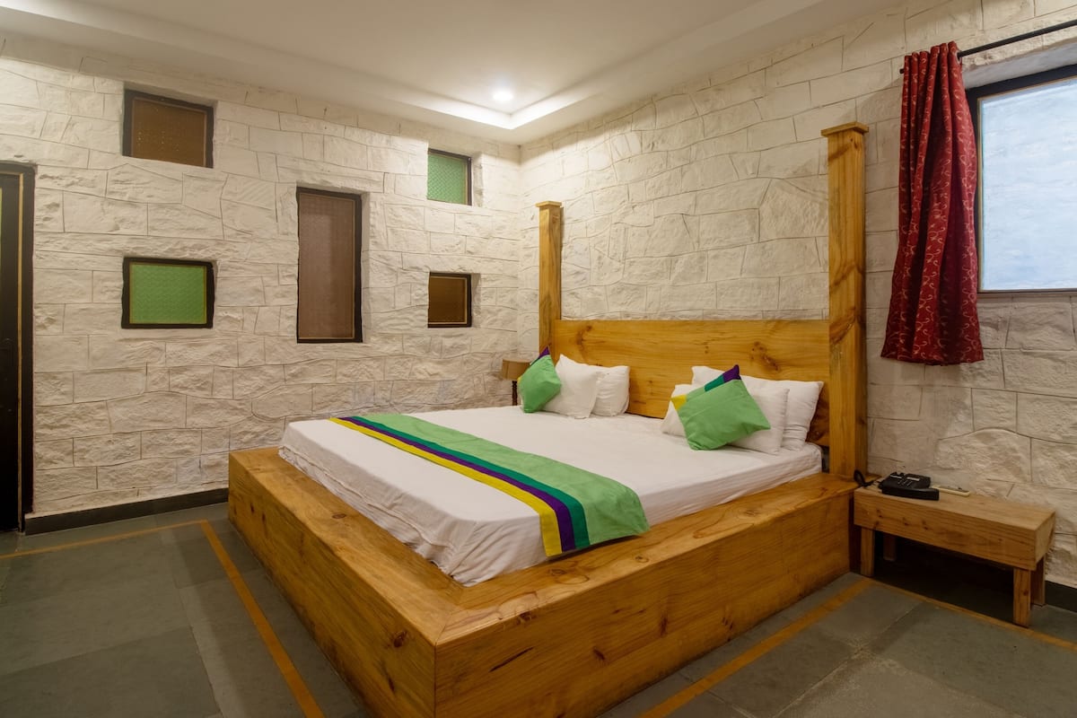 A wooden bed in a room with stone walls and a small window.