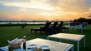 An outdoor dining area with a table, chairs, and plates of food.
