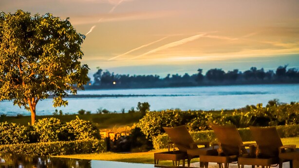 A poolside area with lounge chairs and a view of a body of water.