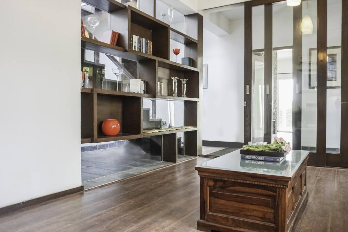 A modern living room with a wooden coffee table, a bookshelf, and a glass partition.