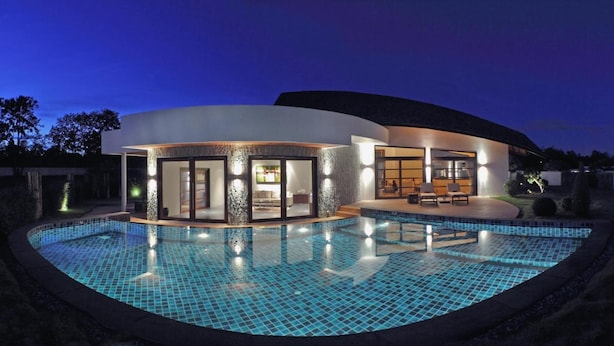 Et moderne hus med swimmingpool, store glasdøre og en patio.