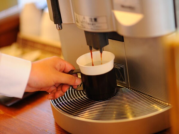 Une main tenant une tasse sous une machine à café qui verse du café.