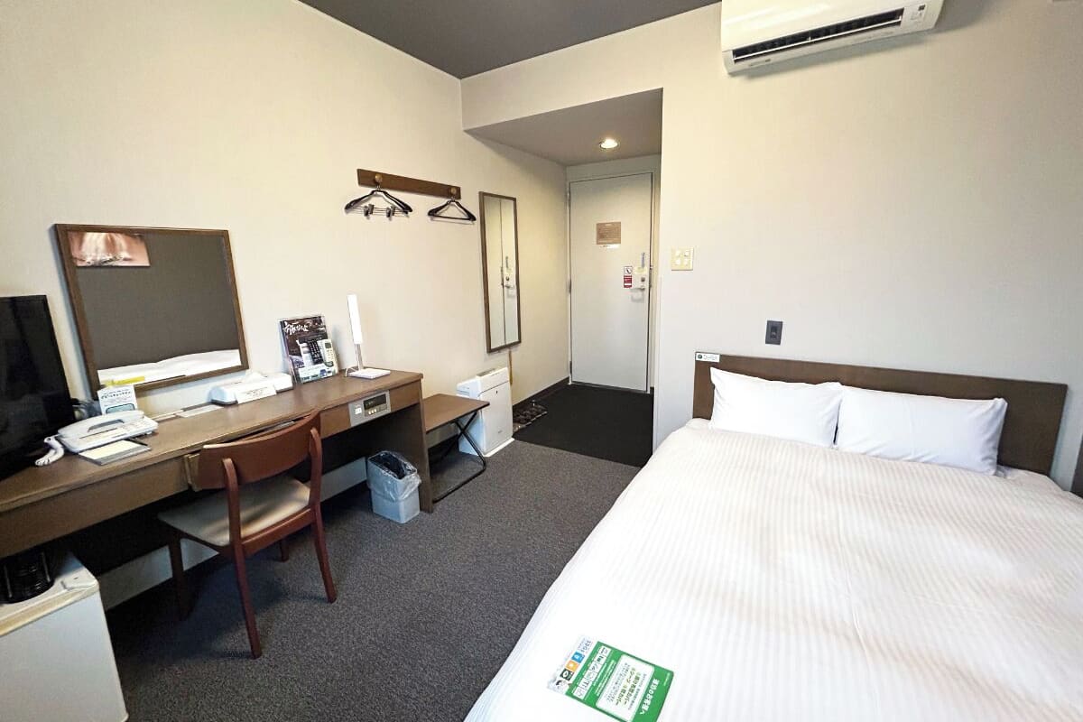 Ein Hotelzimmer mit Bett, Schreibtisch, Stuhl und Klimaanlage.