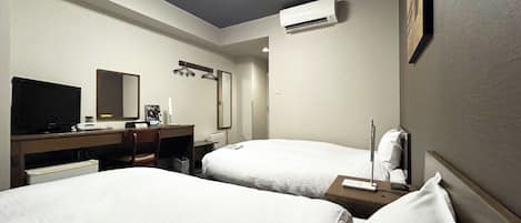 A hotel room with two beds, a desk with a computer, a TV, and an air conditioning unit.