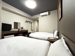 A hotel room with two beds, a desk with a computer, a TV, and an air conditioning unit. - Hotel Route Inn Myoko Arai (Myoko)