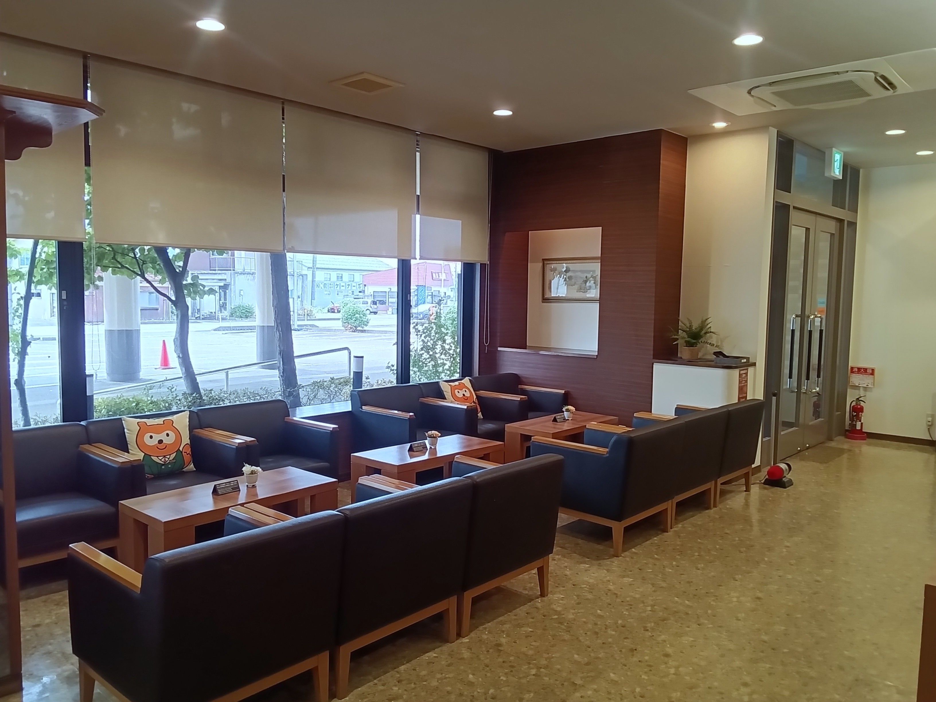 Rebedor d'hotel amb zones d'seure, una recepció i vista al carrer.