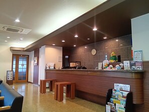 A reception area with a wooden counter, a clock, and a mascot figure. - Hotel Route Inn Myoko Arai (Myoko)