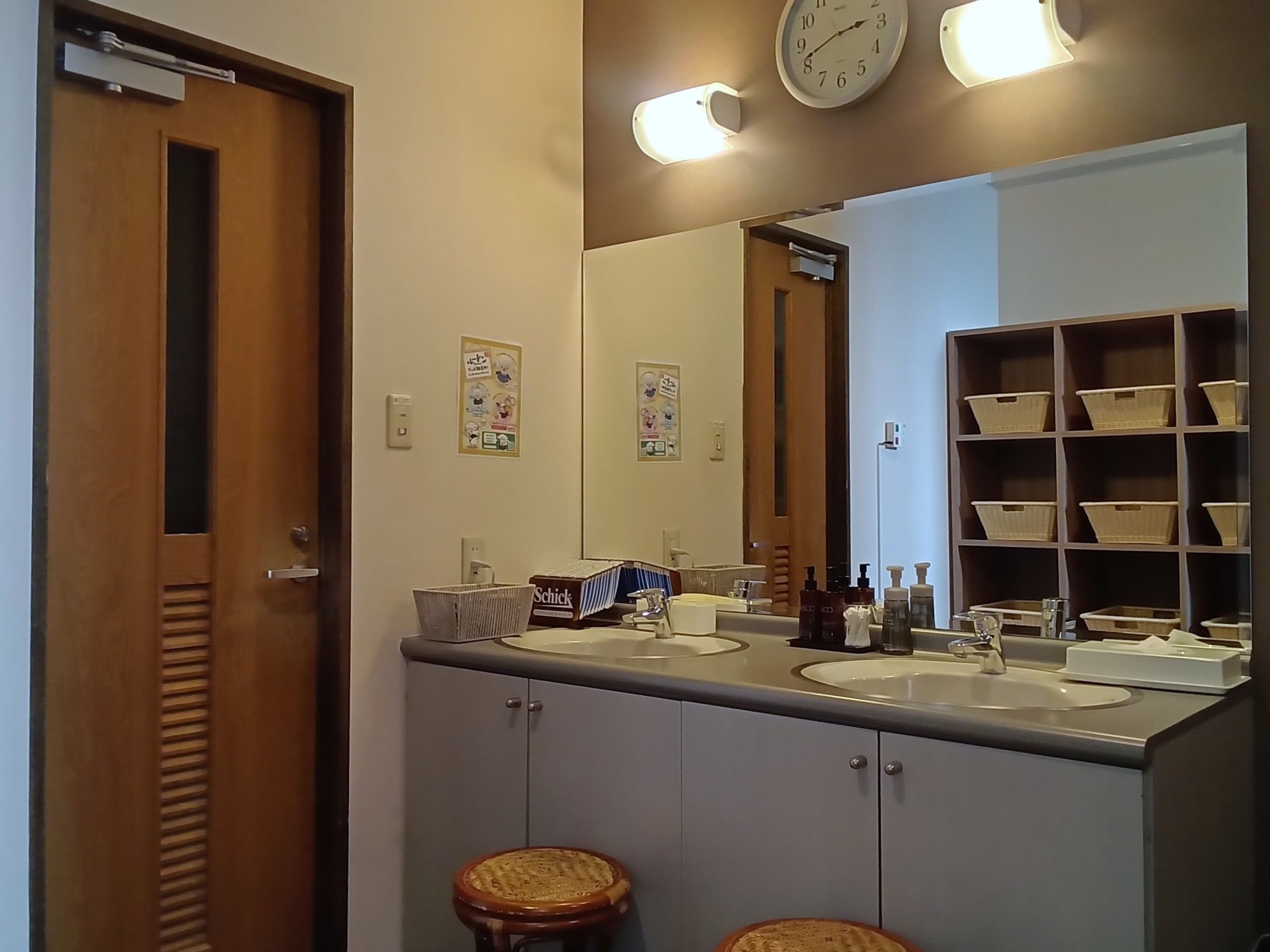 Ein Badezimmer mit zwei Waschbecken, einem Spiegel und einem Regal mit Körben.