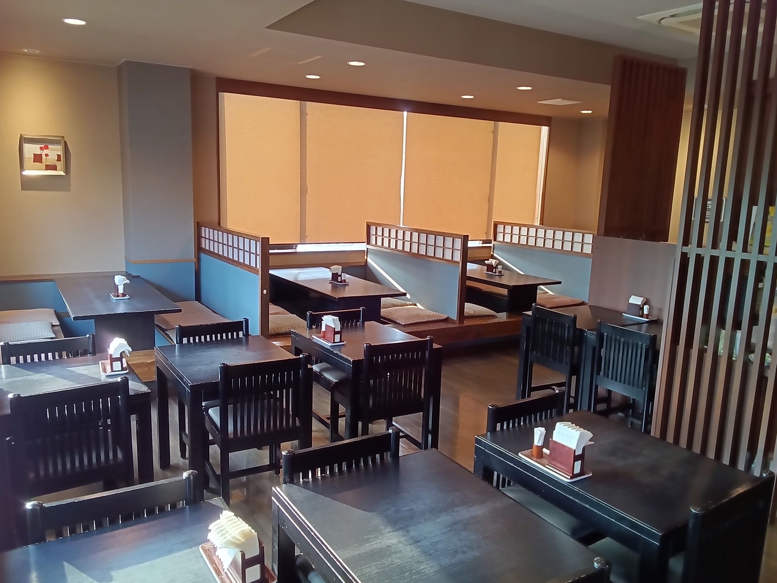 Ein Restaurant mit Sitzecken und Tischen, einige mit Kissen.