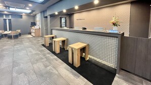 A reception area with a counter, seating, and a tiled wall. - Hotel Route Inn Nagaoka Ekimae (Nagaoka)