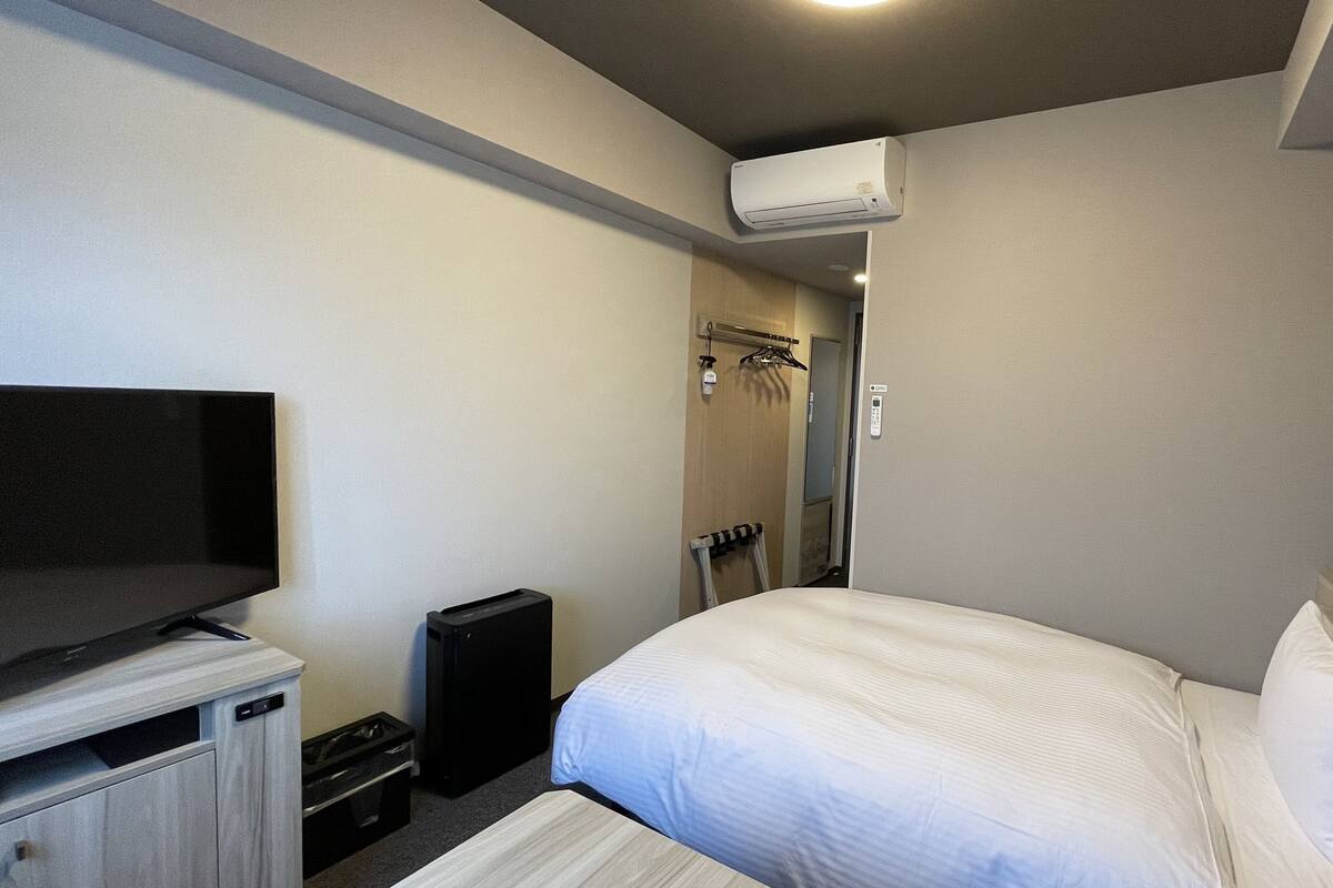 Ein Hotelzimmer mit Bett, Fernseher, Lautsprecher und einer Duschkabine.