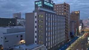 A modern building with a prominent 'Route Inn' sign, featuring a rooftop terrace and a parking area. - Hotel Route Inn Nagaoka Ekimae (Nagaoka)