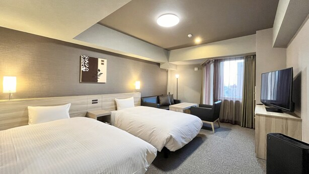 A hotel room with two beds, a desk, a chair, a TV, and a window with curtains. - Hotel Route Inn Nagaoka Ekimae (Nagaoka)