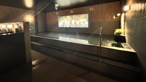 A modern indoor pool area with a large digital screen displaying colorful visuals, surrounded by wooden walls and equipped with a glass barrier. - Hotel Route Inn Nagaoka Ekimae (Nagaoka)