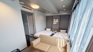 A hotel room with a bed, a sofa, a small table, and a window with curtains.