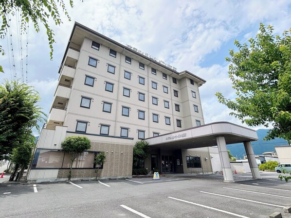 A multi-story hotel with a flat facade, a covered entrance, and a parking lot.