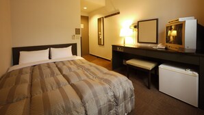 A hotel room with a bed, a desk, a small refrigerator, a lamp, and a television.