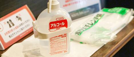 A bottle of Alcolol and a package of green tissue on a wooden surface.