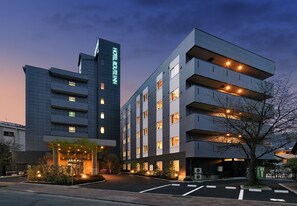 Un hotel moderno con un llamativo letrero 'HOTEL ROUTEM', varios pisos y una zona de entrada bien iluminada.