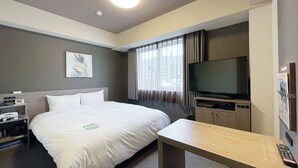 Une chambre d’hôtel avec un lit, un bureau, une télévision et une fenêtre avec des rideaux.