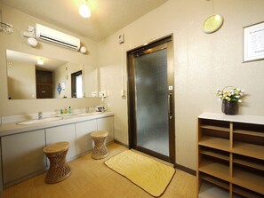 A bathroom with a sink, mirror, and toilet. There is a shower door and a small shelf with a vase of flowers. - Hotel Route-Inn Komoro (Komoro)