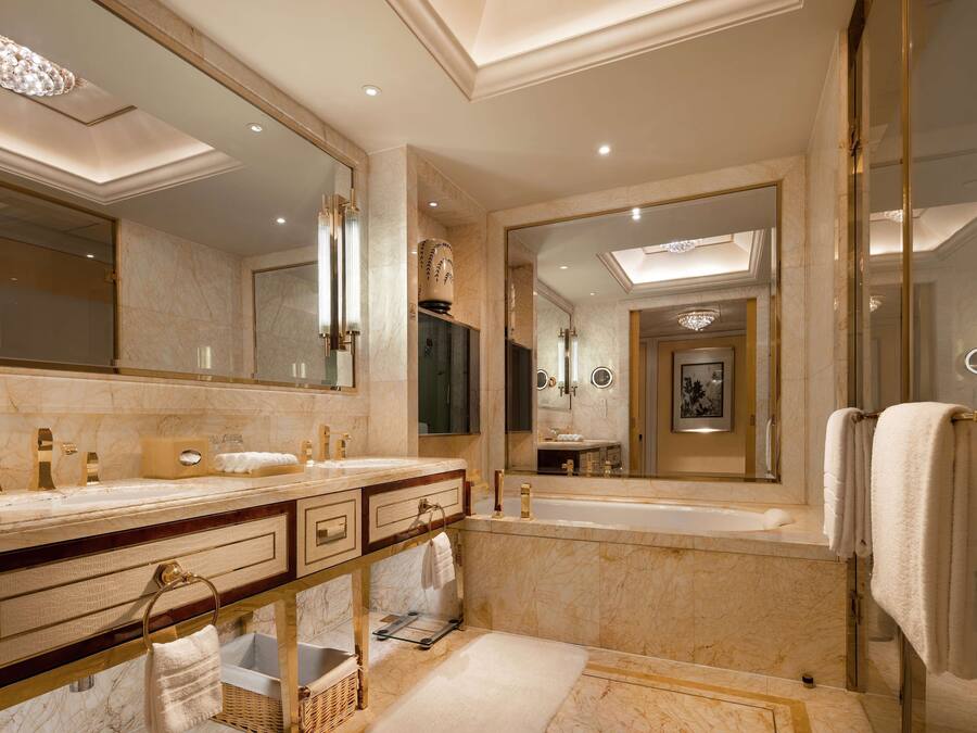 A luxurious bathroom with marble countertops, dual sinks, a large mirror, and a bathtub.