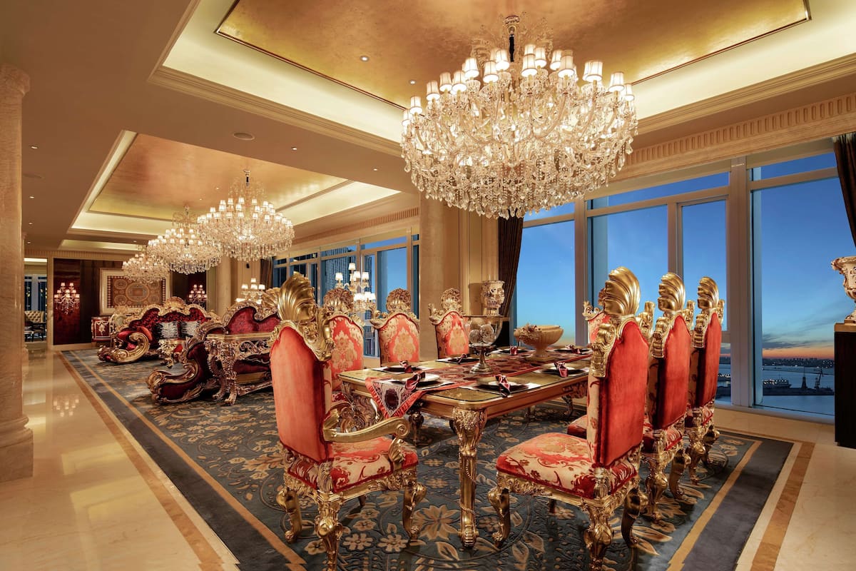 Ein luxuriöser Speisesaal mit aufwendigen Kronleuchtern, rot gepolsterten Stühlen und einem großen Tisch.