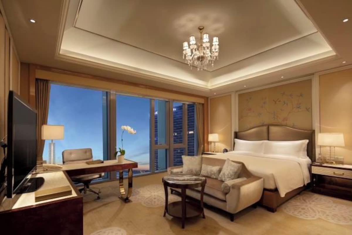 A spacious hotel room with a large bed, a desk, a sofa, and a TV.