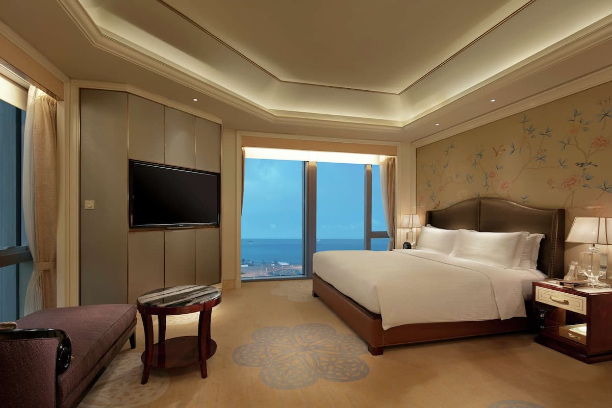 Ein Hotelzimmer mit einem großen Bett, einem Flachbildfernseher, einer Sitzecke und Blick auf den Ozean.