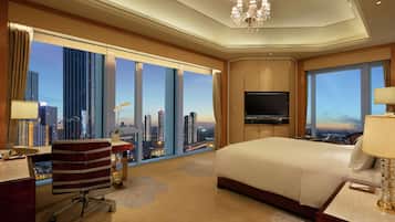 Habitación de hotel con una cama grande, un escritorio con silla, un televisor y vistas a la ciudad.