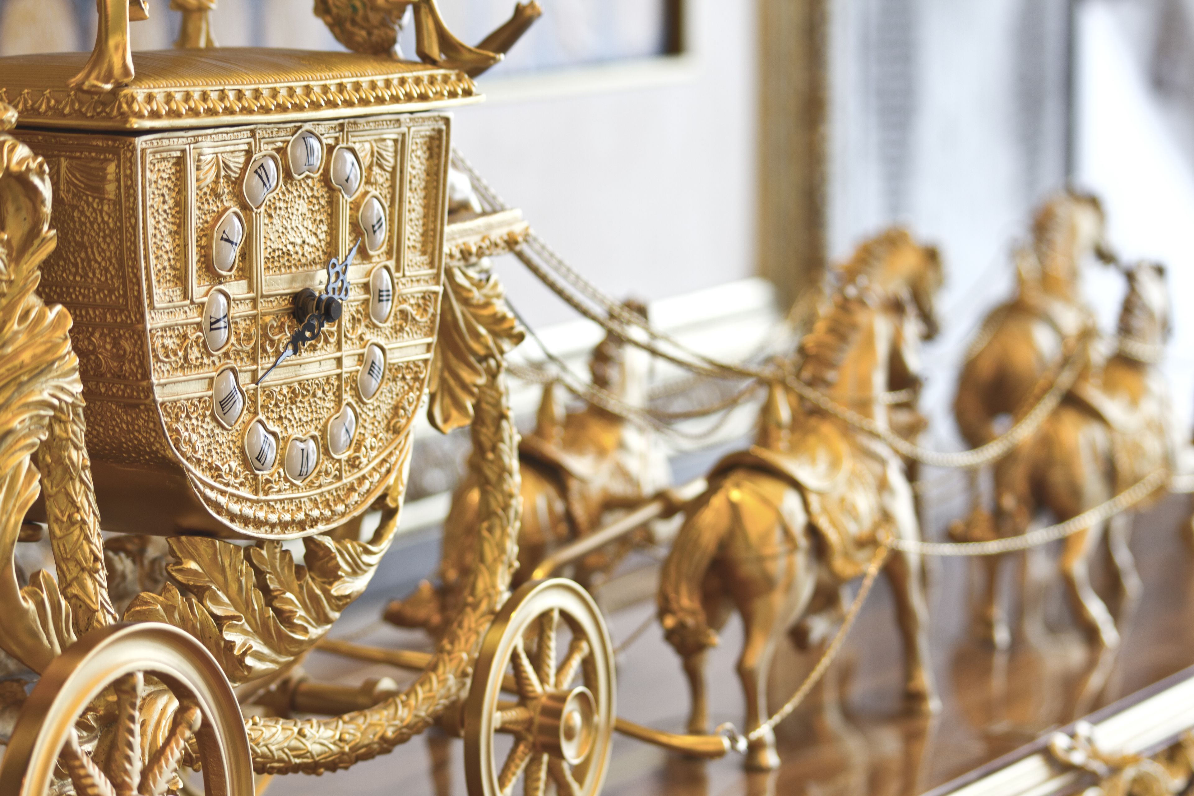 Un carruaje dorado con detalles intrincados y una esfera de reloj.