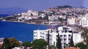 A coastal cityscape with white buildings, some with solar panels, and a view of the sea. - Hotel Melike (Kusadasi)