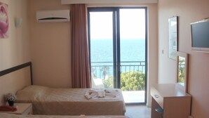 A hotel room with two beds, a desk, and a large window with a view of the sea. - Hotel Melike (Kusadasi)