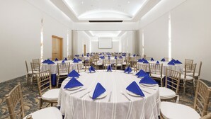 Une salle de conférence avec des tables rondes, des chaises et des serviettes de table bleues.