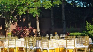 An outdoor dining area with tables and chairs, a pool, and surrounding greenery.