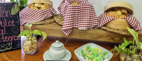 Een houten tafel met broedmanden, een schaal kaas en een bordje met de tekst 'Pan Dulce'.