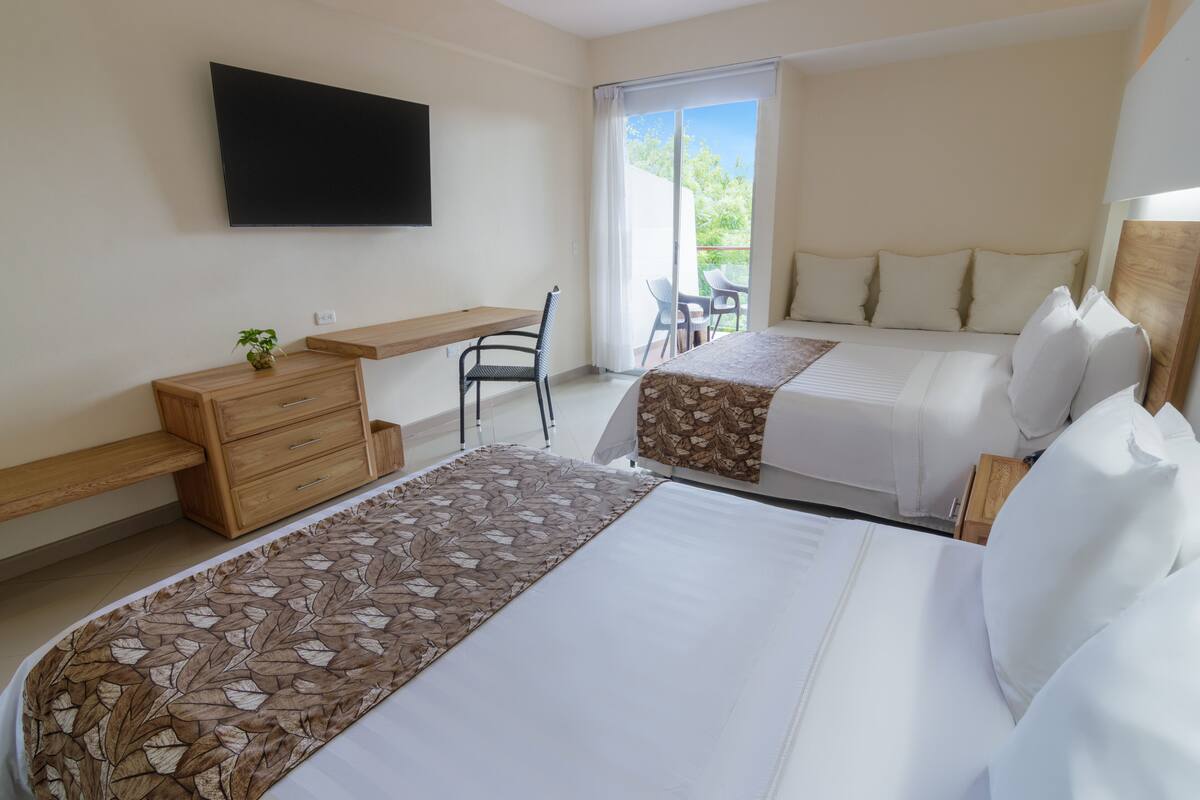 Une chambre d’hôtel avec deux lits, un bureau, une chaise, une télévision et un balcon avec vue.