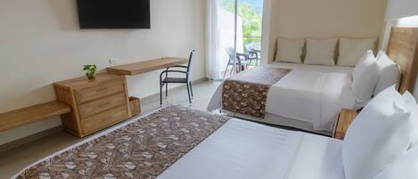 Habitación de hotel con dos camas, un escritorio, una silla, un televisor y un balcón con vistas.