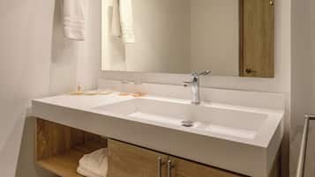A modern bathroom with a white sink, wooden vanity, and a large mirror.