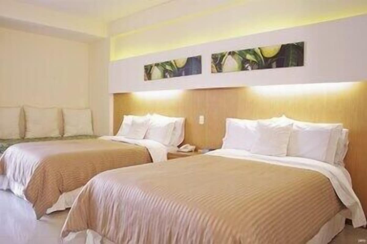 Een hotelkamer met twee bedden, een nachtkastje en een aan de muur bevestigde telefoon.