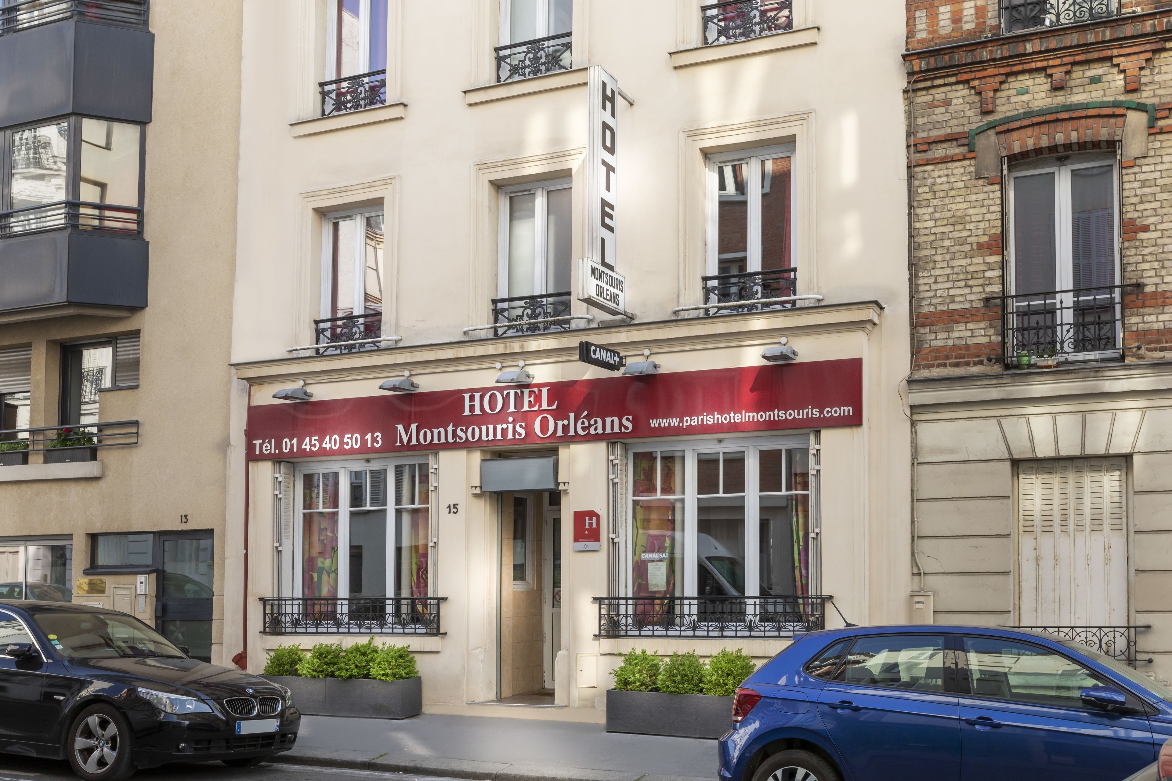 Un hotel con toldo rojo, número de teléfono visible y dirección web.